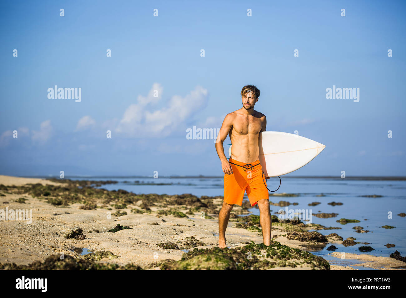 Athletischen Sportler mit Surfen board weg schauen beim Spaziergang am Sandstrand Stockfoto