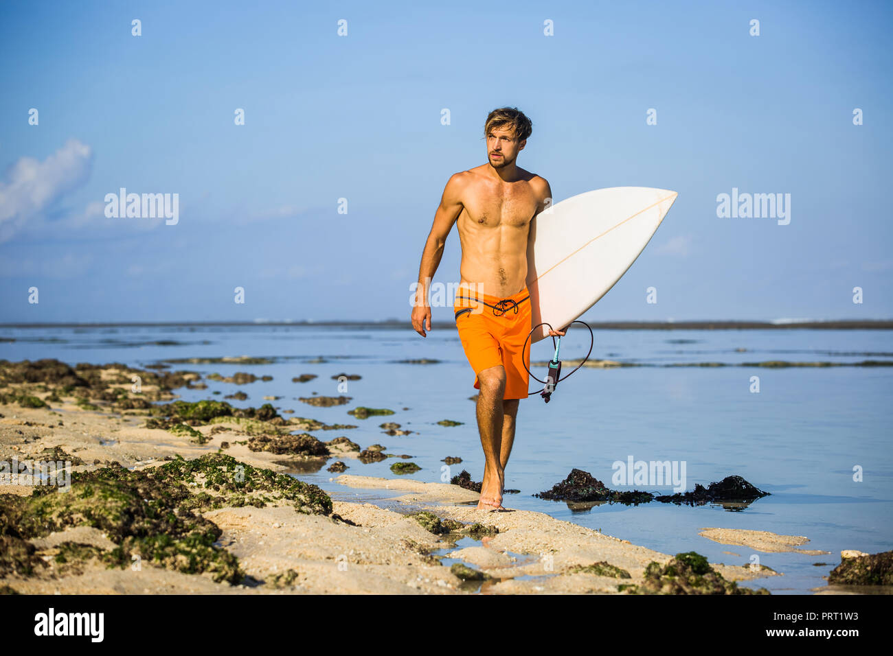 Die jungen Sportler mit Surfen Board zu Fuß am Sandstrand Stockfoto