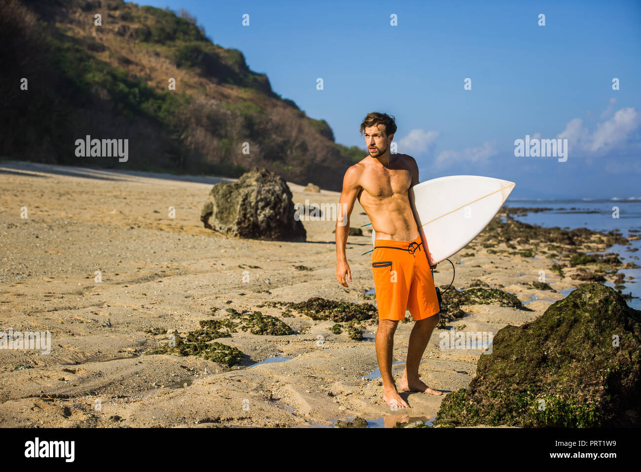 Junge Surfer mit Surfen board stehend auf Sandstrand in der Nähe von Ocean Stockfoto