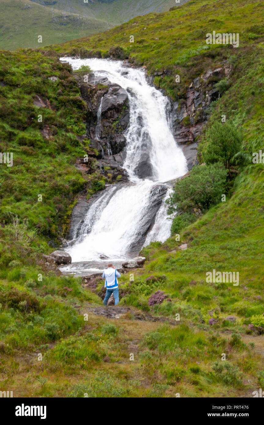 Mann an massiven suchen, donnernden weiß schäumenden Wasserfall, stürzt über eine Lippe in das Tal unterhalb, in Schottland. Stockfoto