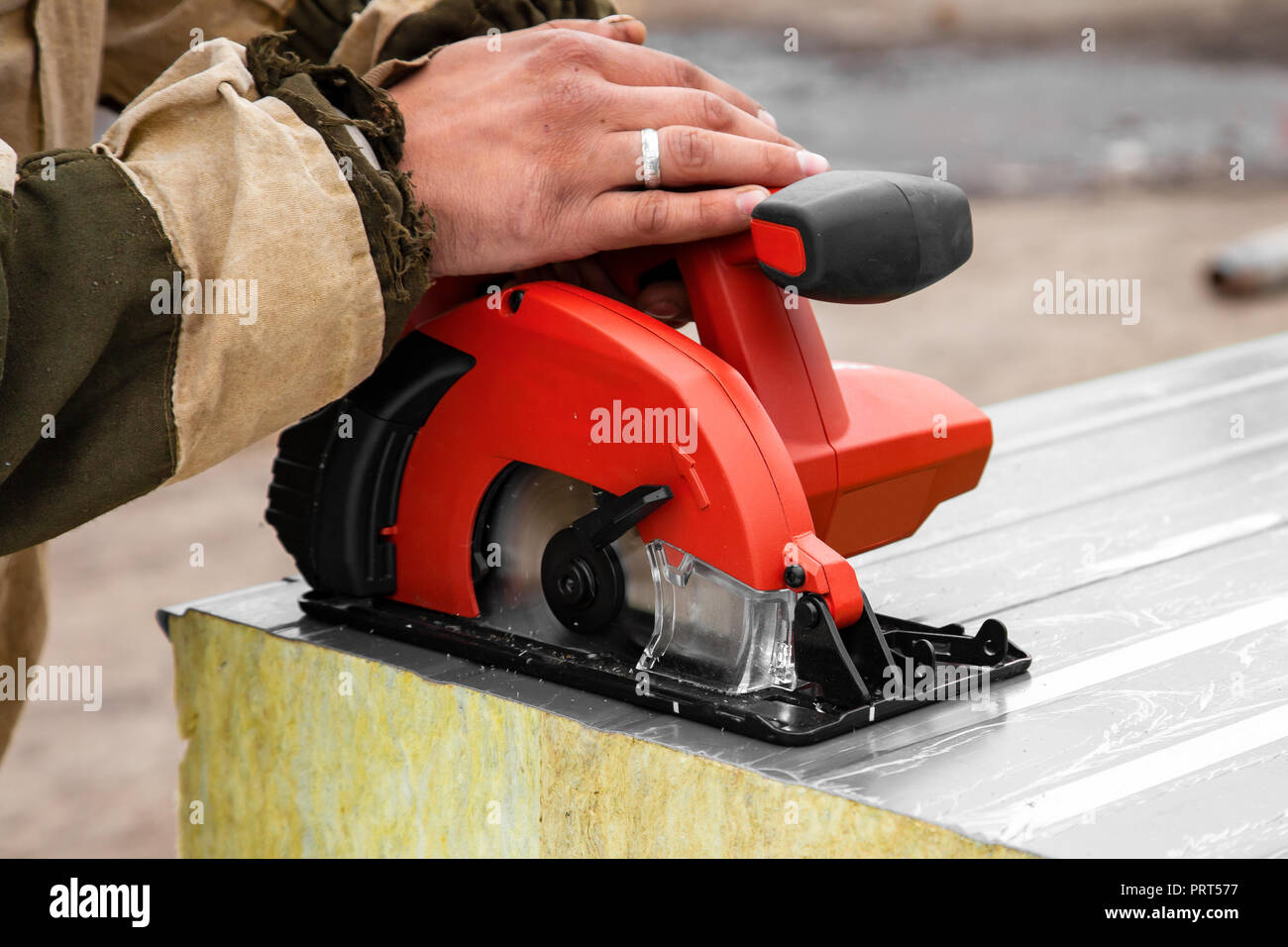 Ein junger Mann, der Schweißer auf einer Arbeiten insgesamt und  Arbeitshandschuhe schleift ein Sandwich Panels mit einem Winkelschleifer in  der constraction Seite Stockfotografie - Alamy