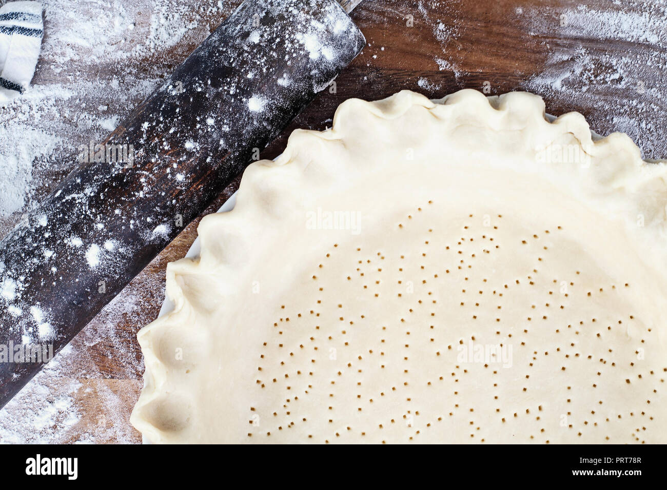 Hausgemachte butter Pie Crust in Pie Platte mit geriffelten Rand gequetscht, nudelholz und extra Ball von Teig über Bemehlten rustikalen Holzmöbeln Hintergrund. Kruste ist Stockfoto