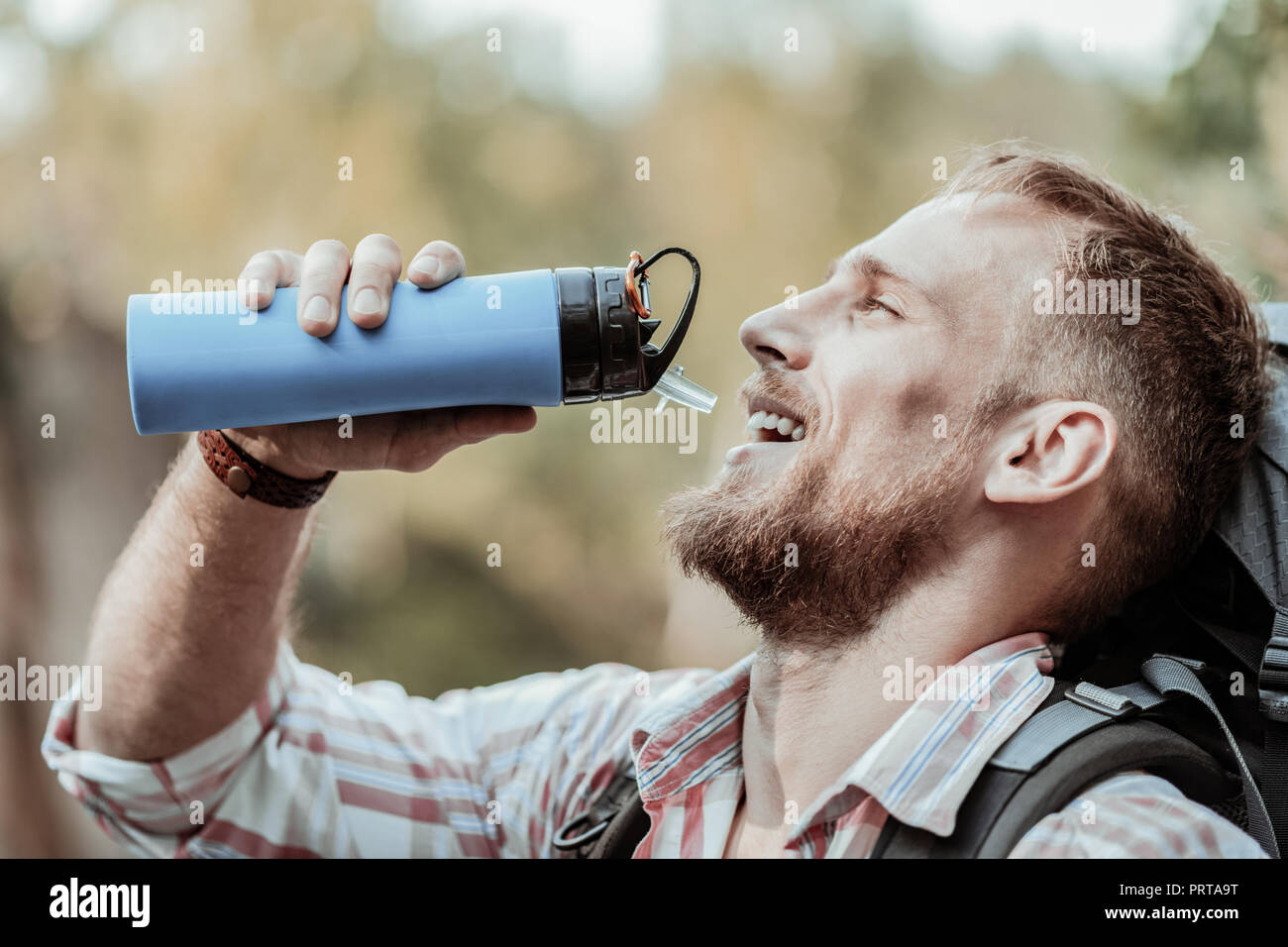 Schöne bärtige dark-eyed man Trinkwasser aus seinem blaue Flasche Stockfoto