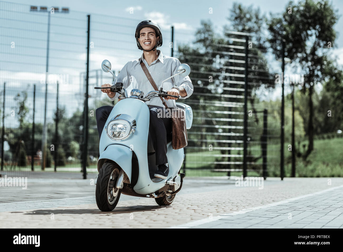 Optimistisch männliche Kursteilnehmer Capping bis zur Universität auf Motorrad Stockfoto