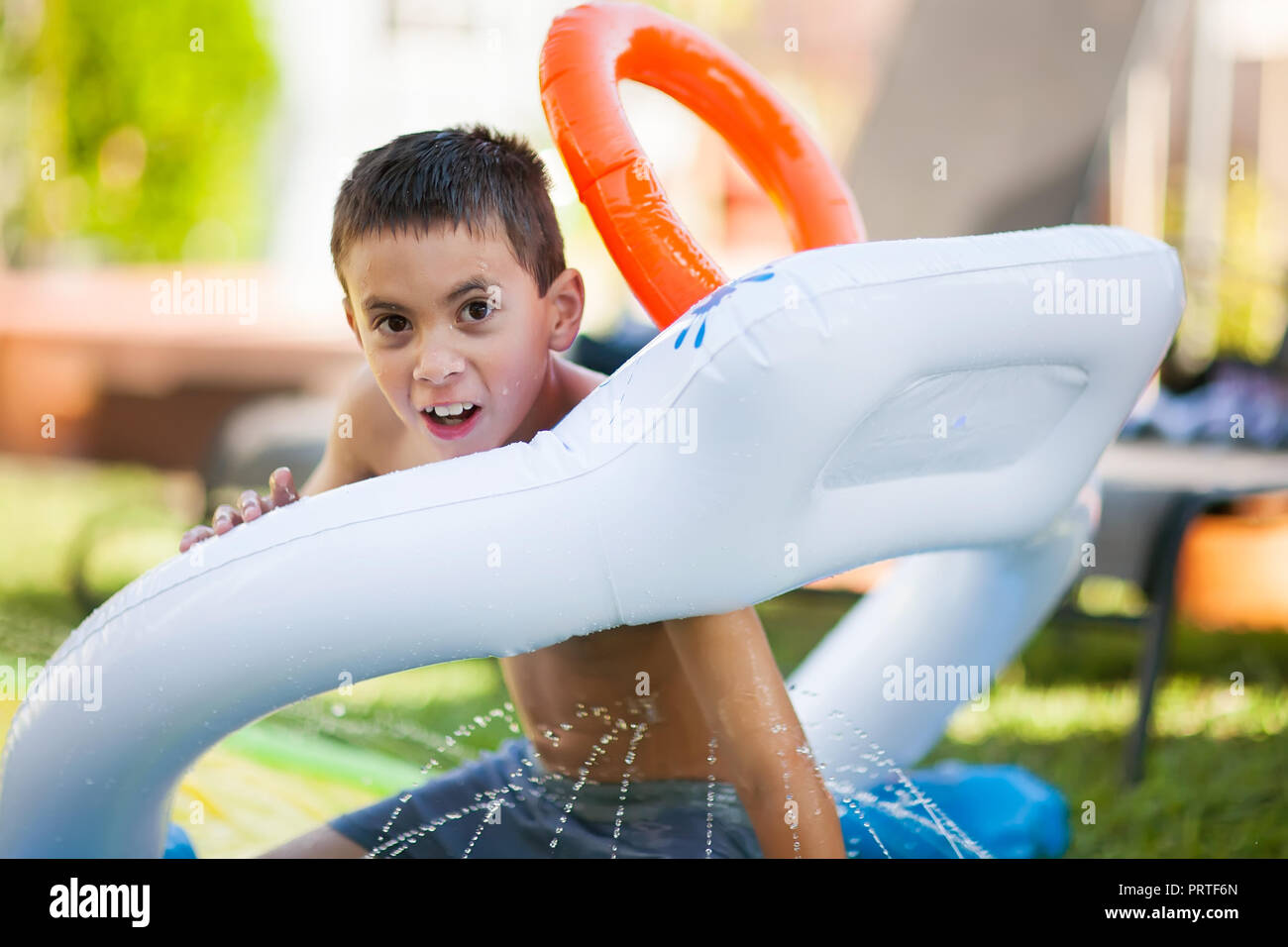 Junge Spritzen in eine Wasserrutsche Spaß im Sommer in einem Hinterhof Stockfoto