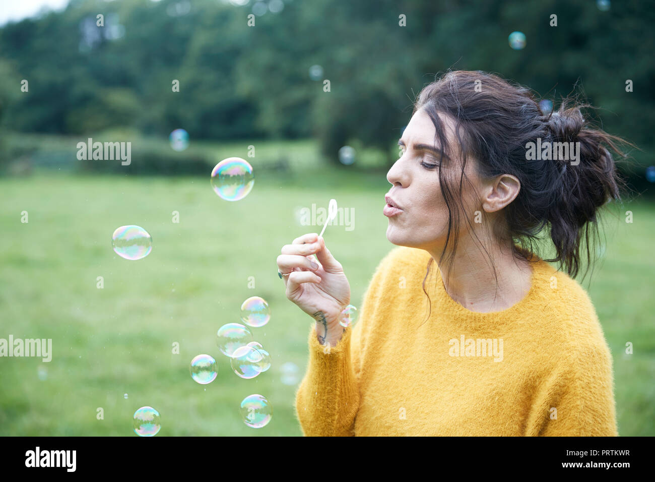 Frau spielen mit Seifenblasen in Feld Stockfoto