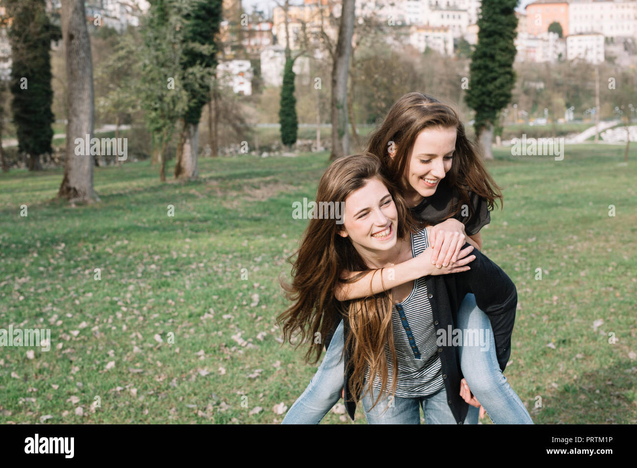 Freundinnen spielen piggyback Ride in Park Stockfoto
