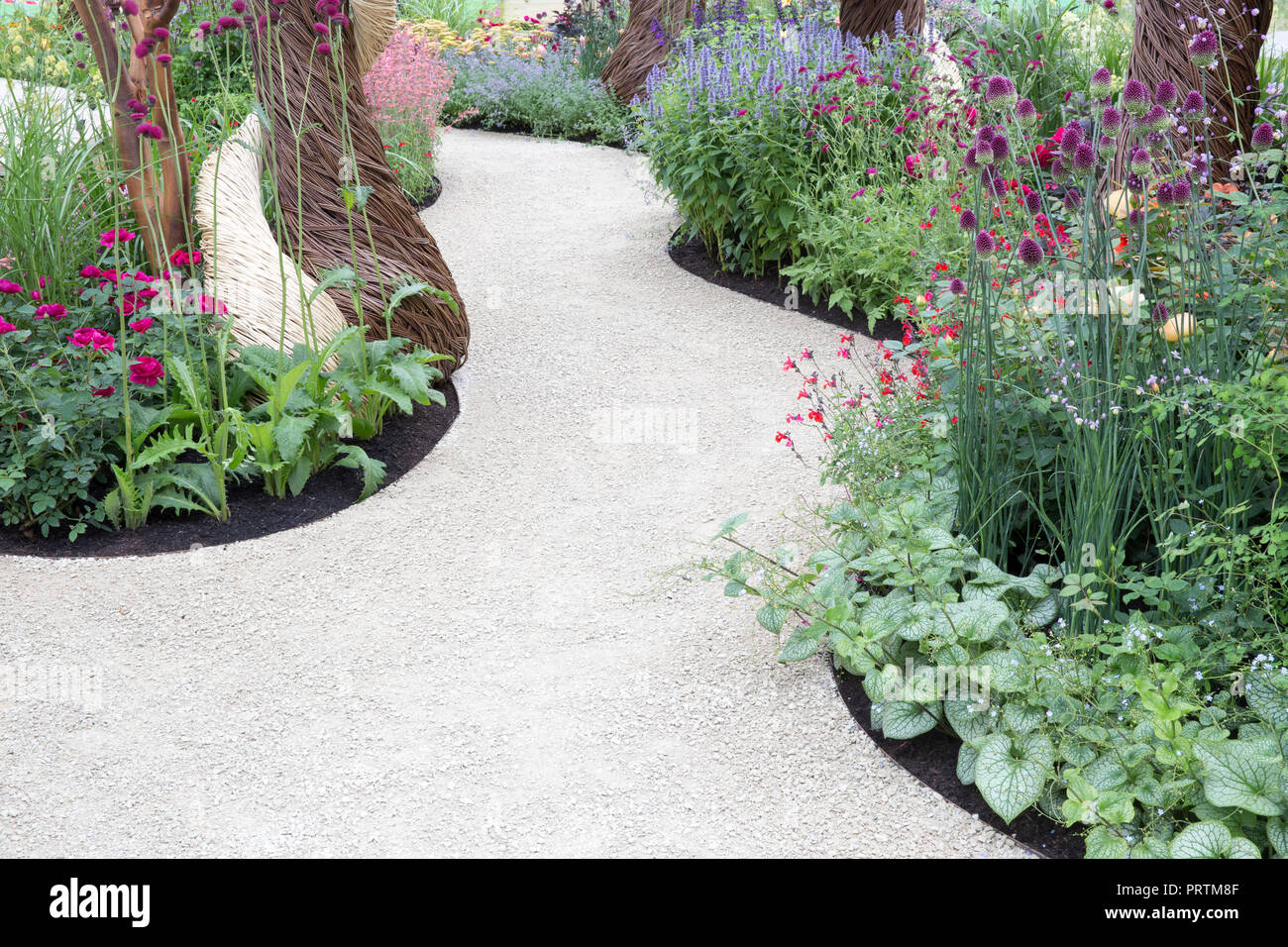 Moderner zeitgenössischer englischer Garten mit einem Kiesweg mit gemischten Blumenbordüren Hampton Court Flower Show England Stockfoto