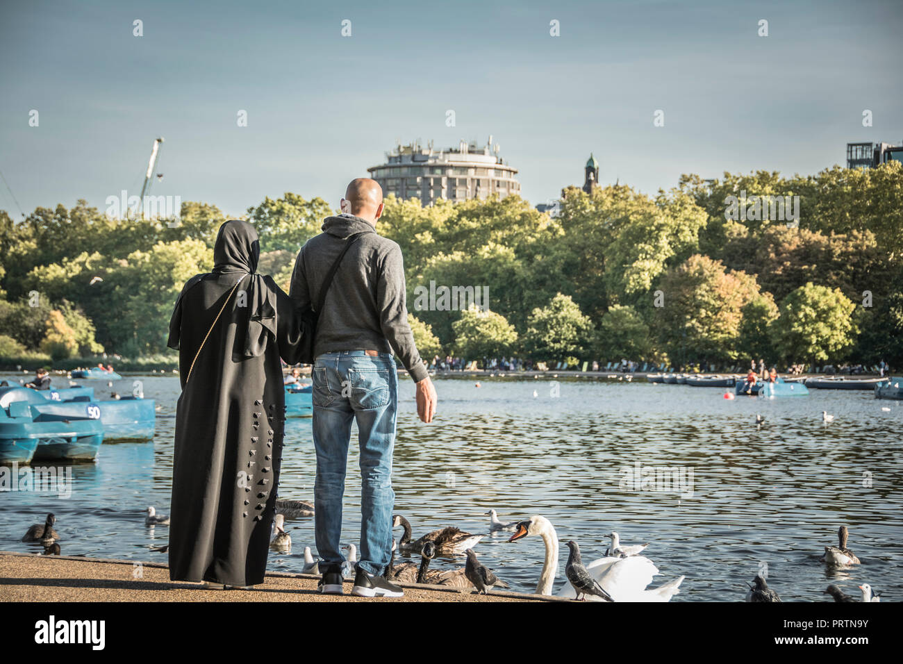 Ein muslimisches Paar füttern die Enten am Ufer der Serpentine, London, UK Stockfoto