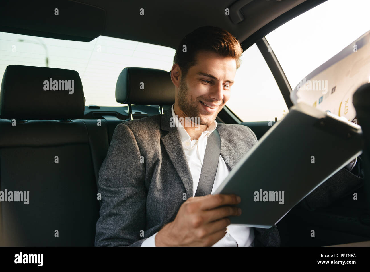 Gut aussehender Geschäftsmann durch Dokumente, während an der Rückseite eines Auto sitzen Stockfoto
