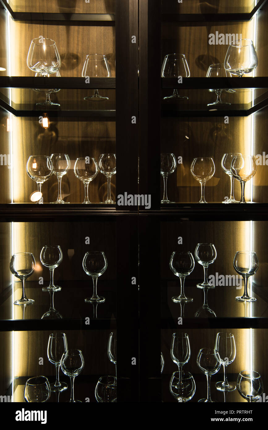 Unterschiedliche Gläser auf Regalen in Küche mit dunklen Licht Stockfoto