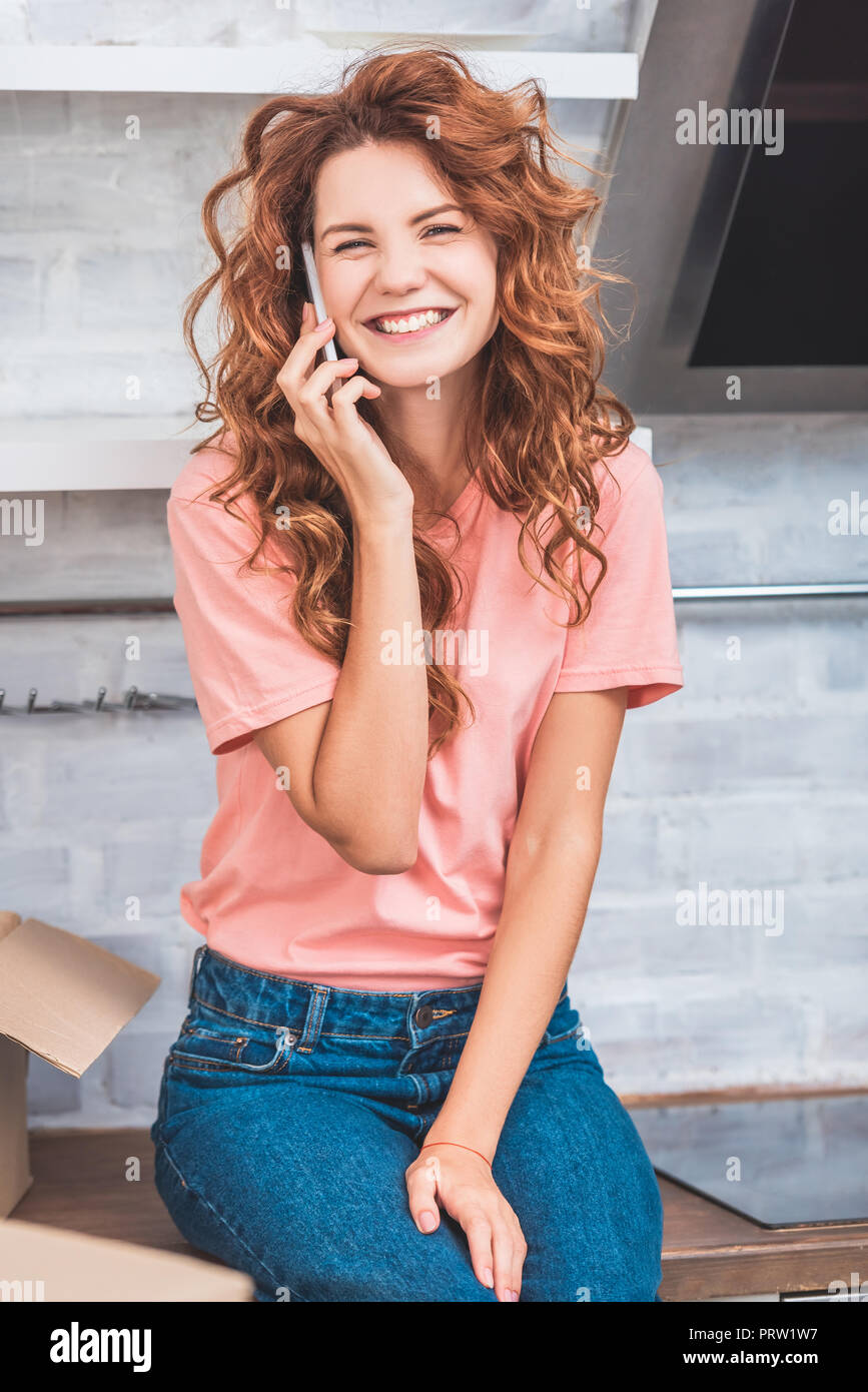 Glückliche junge Frau spricht von Smartphone und lächelnd an der Kamera beim Umzug Stockfoto