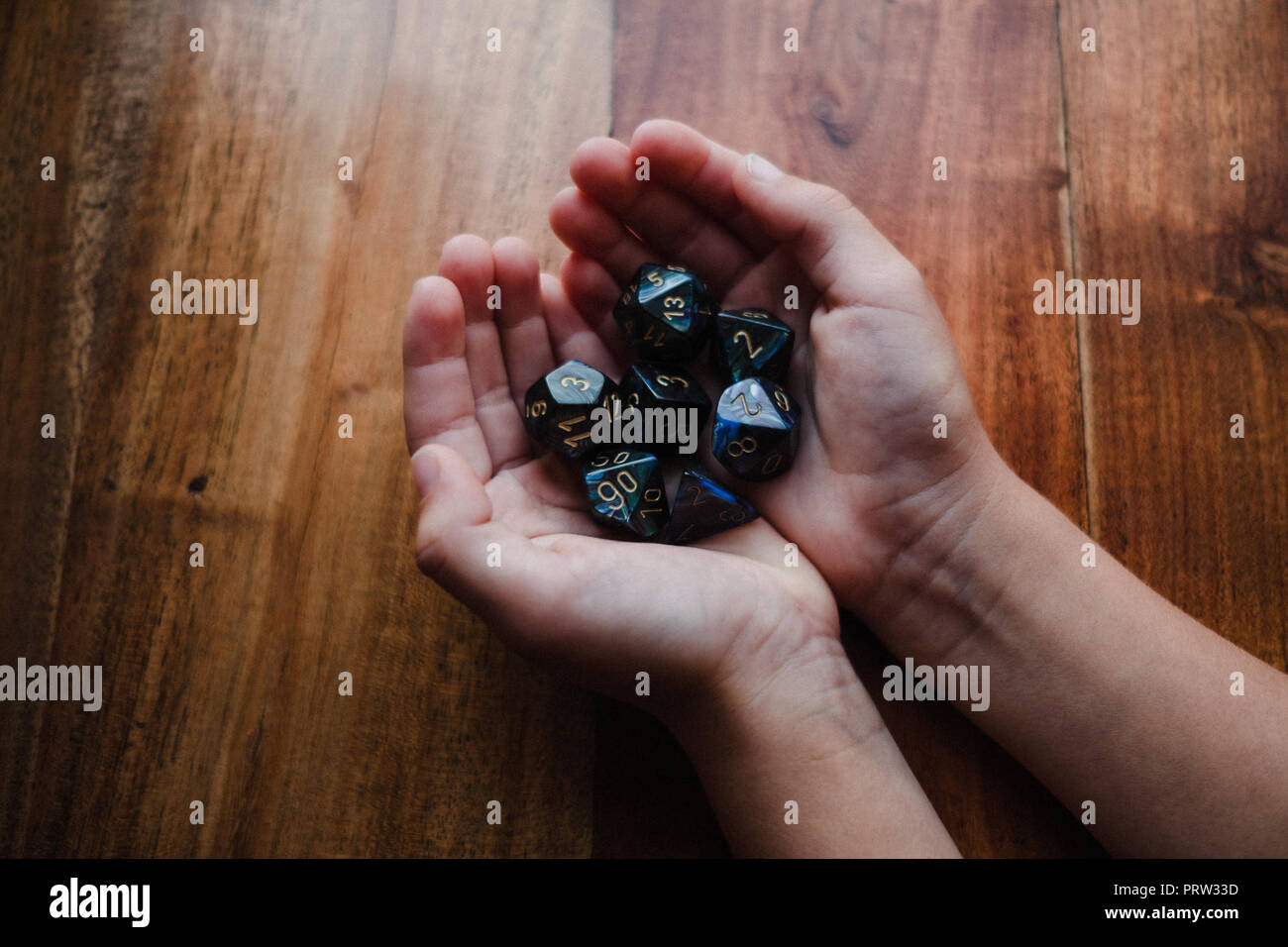 Mädchen mit hohlen Händen am Tisch holding Rolle zu würfeln, Nahaufnahme Stockfoto