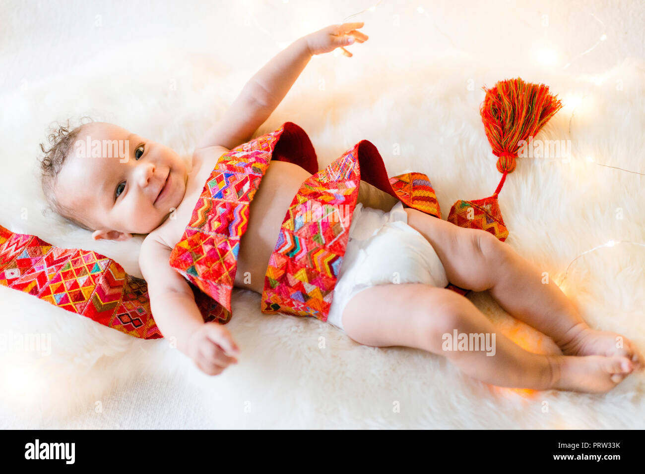 Baby Boy verpackt in bunten Textilien liegen auf flauschigen Teppich Stockfoto
