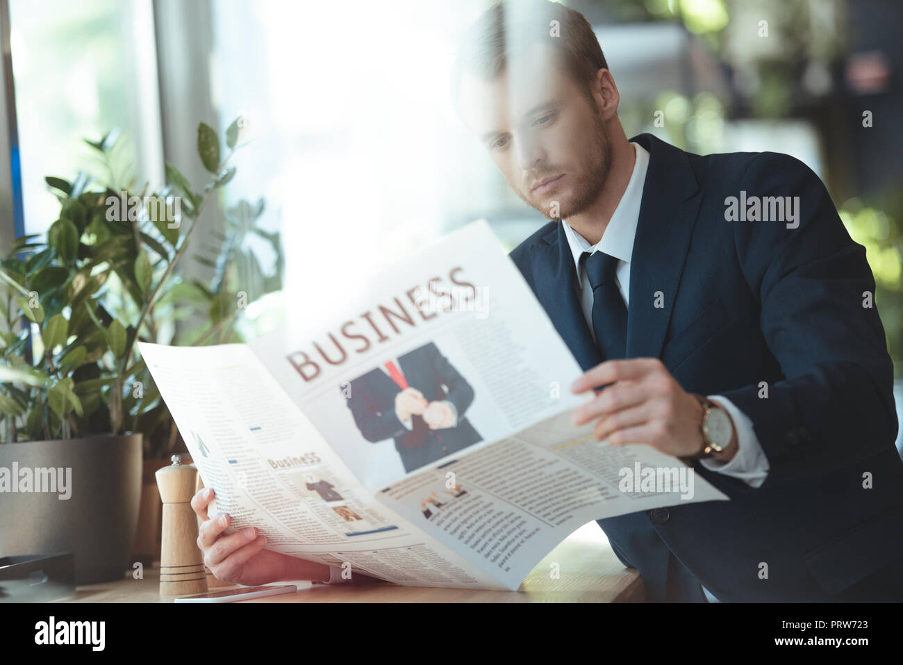 Konzentrierte Geschäftsmann in Anzug lesen Zeitung im Cafe Stockfoto