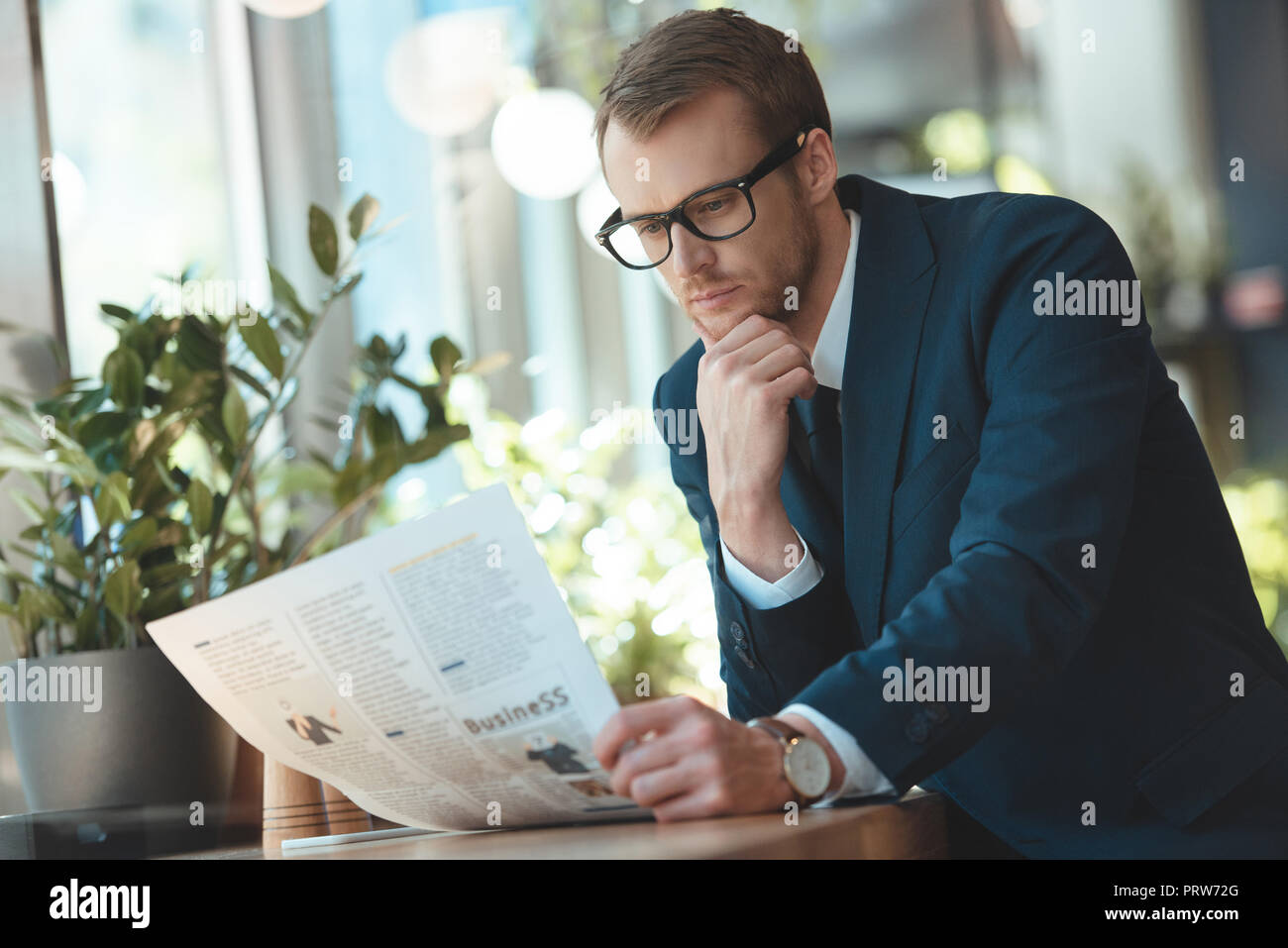 Konzentrierte Geschäftsmann in Brillen lesen Zeitung im Cafe Stockfoto