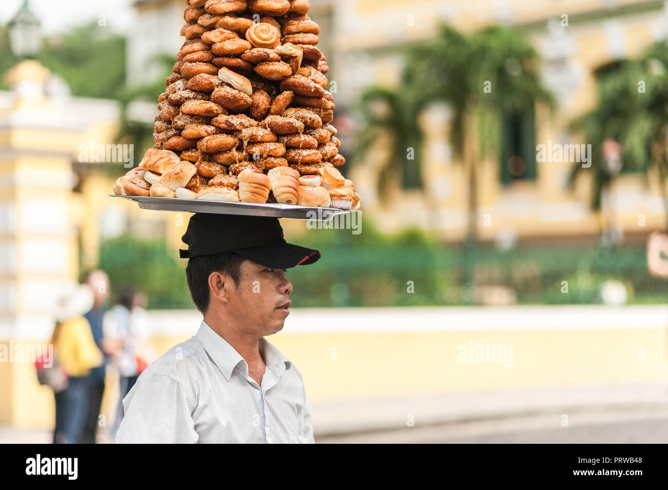 Ho Chi Minh City, Vietman - 21. Oktober 2016. Lokaler Mann Verkauf von Backwaren aus einem Fach, das er auf seinem Kopf trägt. Außerhalb einer alten asiatischen Markt von B Stockfoto