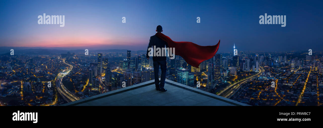 Geschäftsmann in Anzug und Cape Held stand auf der Dachterrasse großartig Stadtbild ansehen und denken Business Plan für die Zukunft. Nacht Szene. Stockfoto