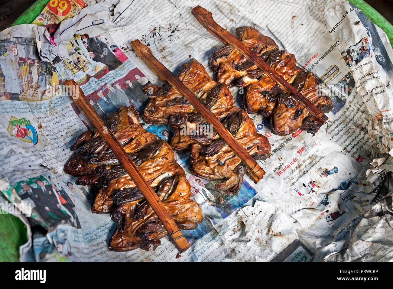 Gebratene grüne Frösche auf Sticks. Eine traditionelle Köstlichkeit auf Eisenbahnschienen Maeklong Markt, Bangkok, Thailand. Stockfoto