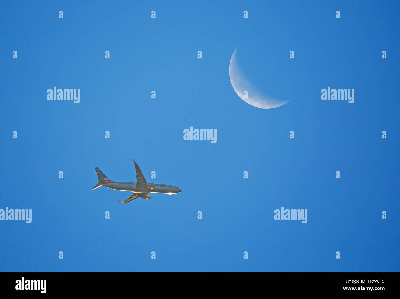 CHARLOTTE, NC (USA) - Oktober 4, 2018: ein Verkehrsflugzeug in niedriger Höhe unter ein Halbmond bei Sonnenaufgang. Stockfoto