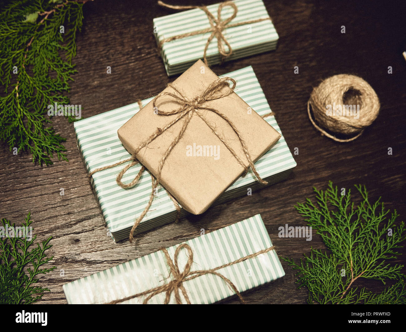 Geschenkbox mit blauer Schleife und Tannenzweigen auf Holz Hintergrund. minimal Weihnachten Neujahr Konzept. Stockfoto