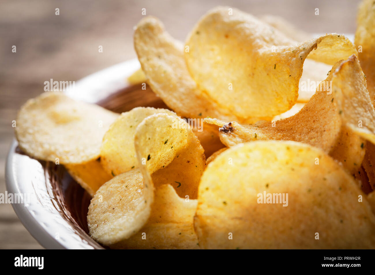 Haufen Kartoffelchips in Schüssel auf Holz- Hintergrund Stockfoto