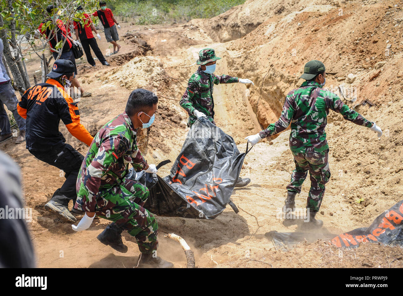 Palu, Sulawesi, Indonesien. 4. Okt, 2018. Offiziere gesehen, indem die Körper der Opfer im Grab Löcher vor der Masse - in Poboya begraben. Eine tödliche Erdbeben der Stärke 7.7 Ausmaß und der Tsunami Welle verursacht durch die Stadt von Palu und viel von der Gegend in Zentral-sulawesi zerstört hat. Nach Ansicht der Beamten, die Zahl der Todesopfer von verheerenden Erdbeben und Tsunami steigt auf 1.347, rund 800 Menschen in Krankenhäuser sind schwer verletzt und rund 62.000 Menschen in 24 Flüchtlingslagern rund um die Region vertrieben worden. Credit: Hariandi Hafid/SOPA Images/ZUMA Draht/Alamy leben Nachrichten Stockfoto