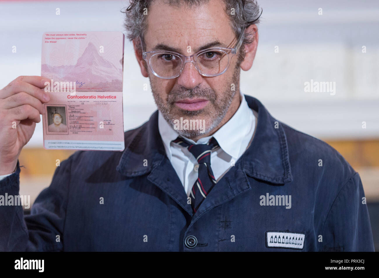 London, Großbritannien. 5. Oktober 2018. Tom Sachs stellt mit einem Pass. Vorschau von 'Swiss Passport Office', die von den amerikanischen Künstler Tom Sachs an Galerie Thaddaeus Ropac in Mayfair. Mit Frieze Week, die Galerie für 24 Stunden von 18:00 Uhr 5 Oktober bis 6:00 Uhr 7. Oktober geöffnet für die Ausgabe der seriellen bleiben zusammenfallen - nummerierte Tom Sachs Schweizer Pass für die Besucher. Die Installation spiegelt die Sorgen um den Brexit, Syrien und Donald Trump's Einwanderungspolitik und Herausforderungen der Begriff der globalen Verantwortung. Credit: Stephen Chung/Alamy leben Nachrichten Stockfoto