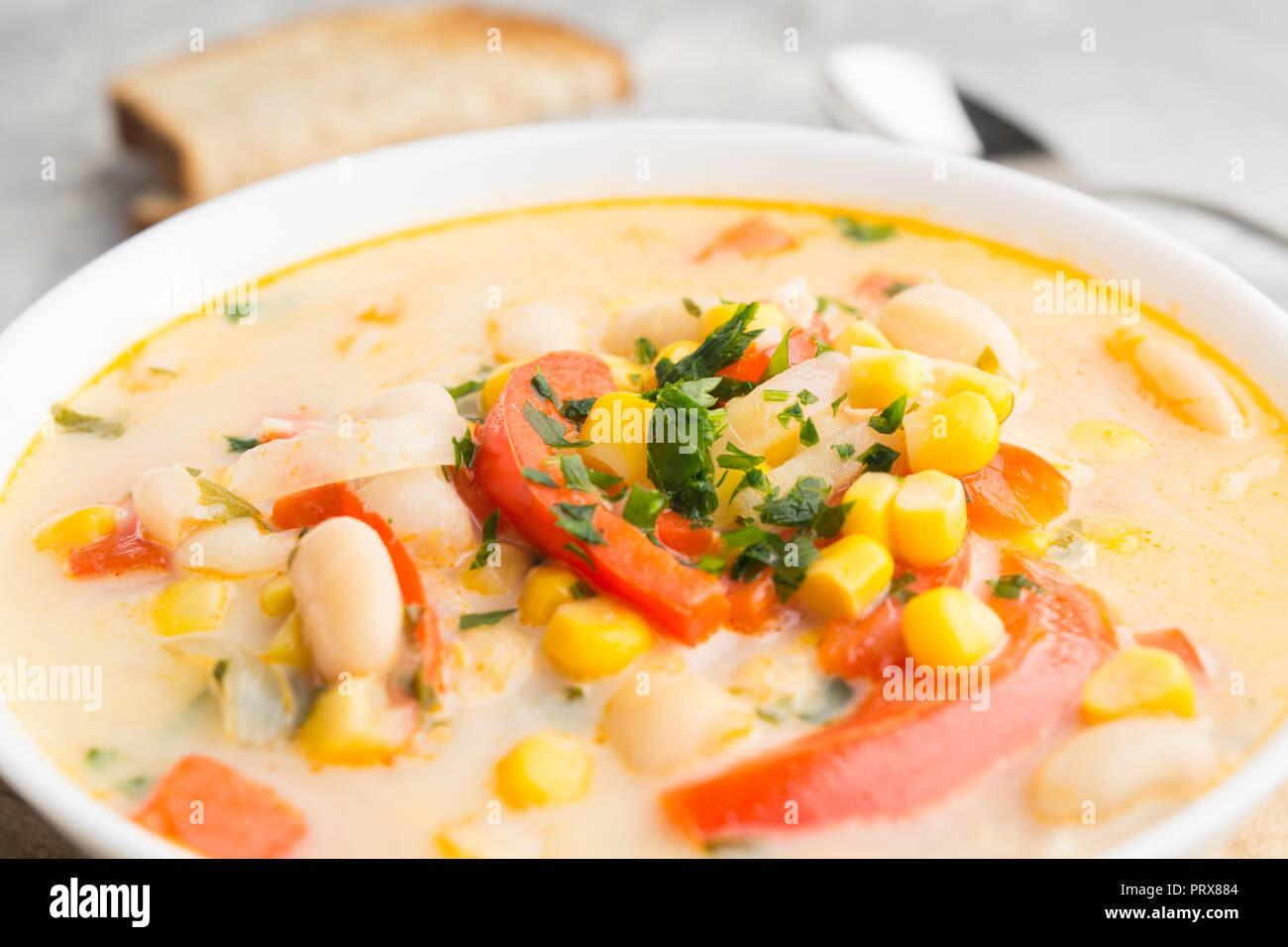 Cremesuppe mit Mais, Bohnen, Zwiebeln, Pfeffer. Detailansicht mit Brot auf Hintergrund Stockfoto