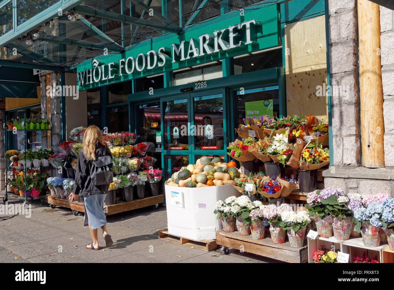 Junge blonde Frau zu Fuß vorbei an der Whole Foods Market auf West 4th Avenue in der Kitsilano-viertels von Vancouver, BC, Kanada Stockfoto