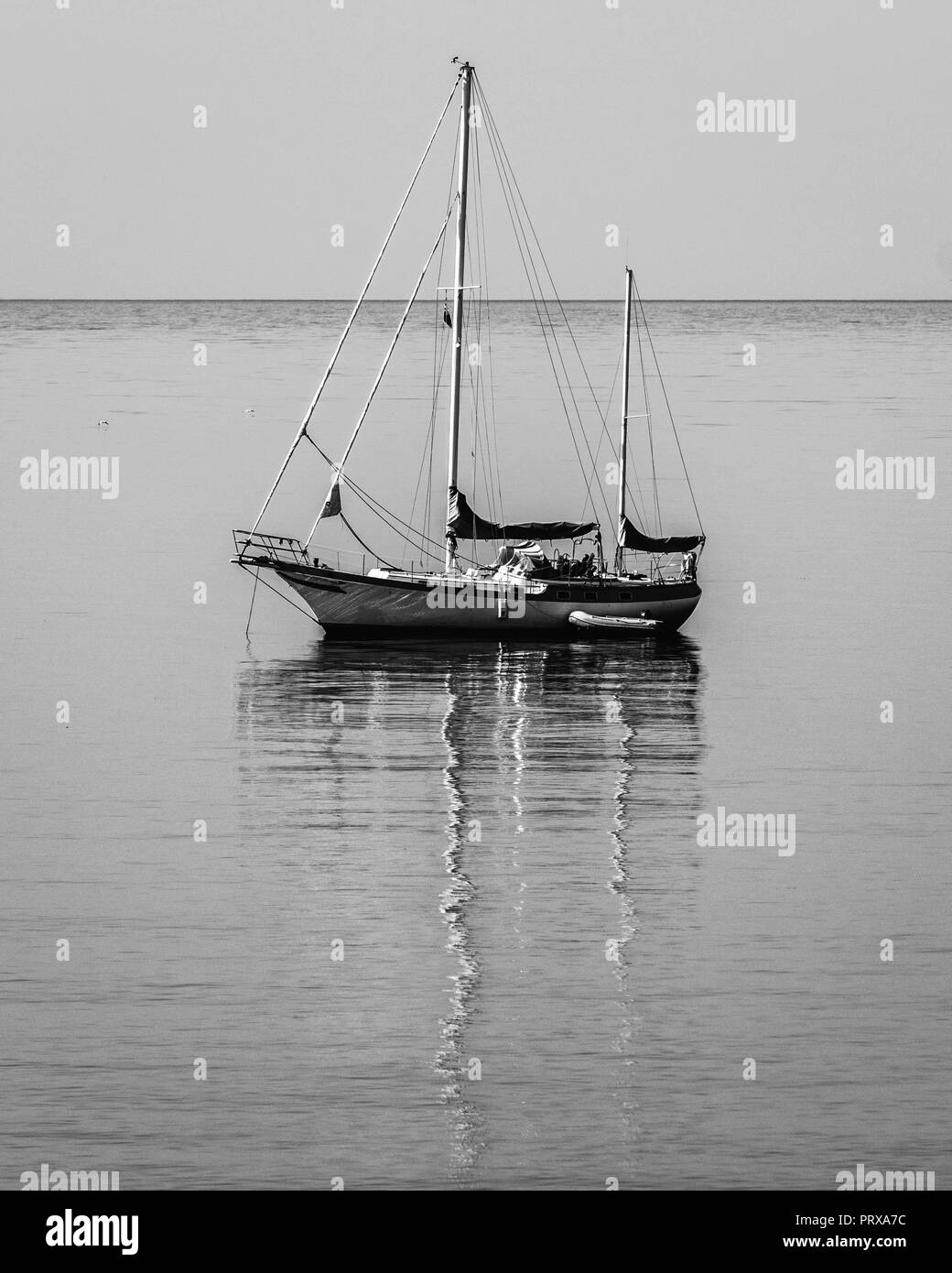 Ein Segelboot und Reflexion über den Ozean weg von Budleigh Salterton, East Devon, Südwest-England, Vereinigtes Königreich. Stockfoto