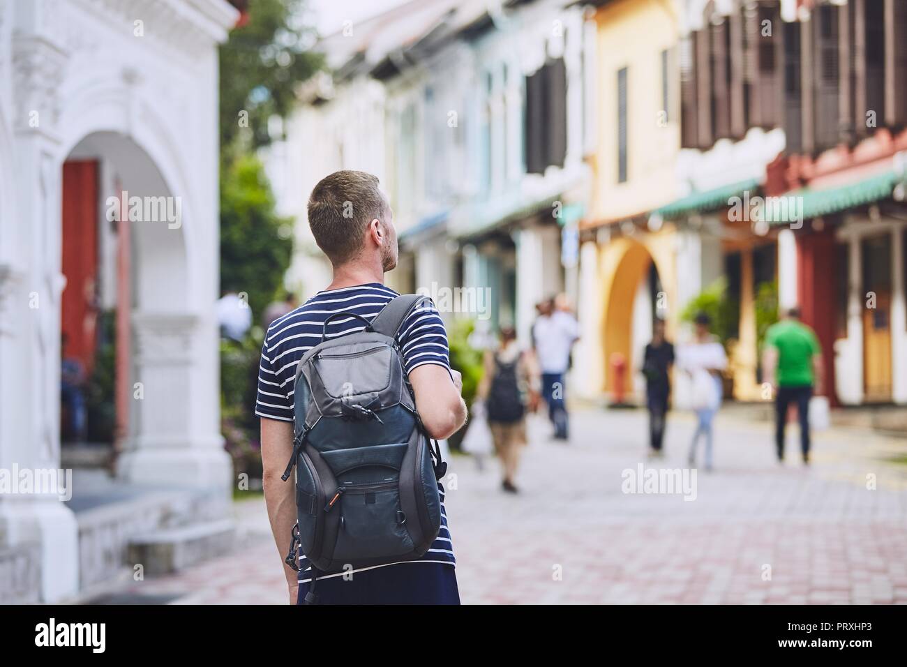 Reisende in die Stadt. Junger Mann mit Rucksack bewundern Sie die Architektur der alten Häuser in Singapur. Stockfoto