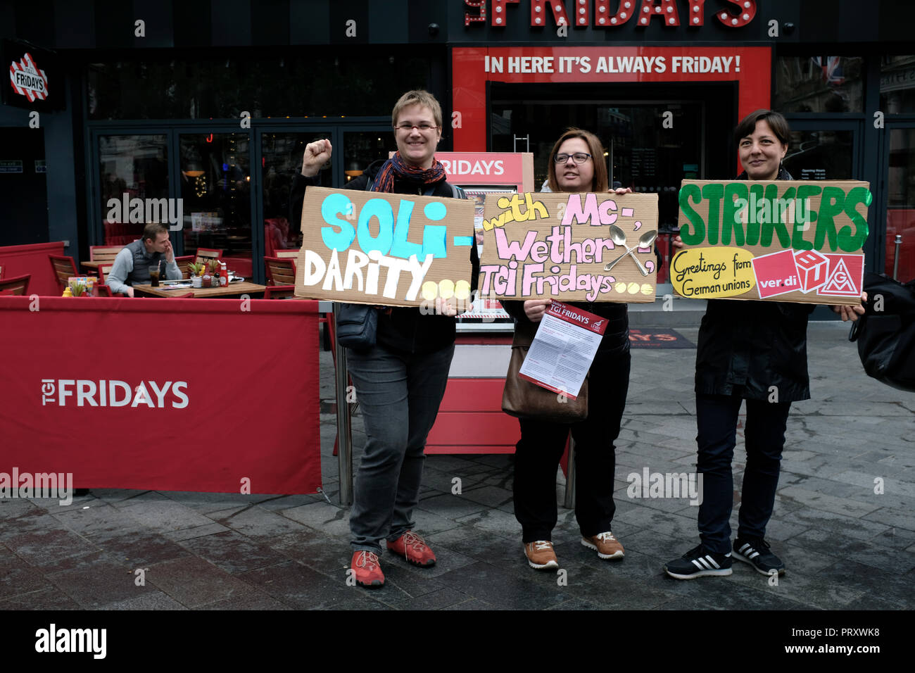 Die demonstranten gesehen halten Plakate vor einem TGI Fridays während des Protestes. Wetherspoons, TGI Fridays, und McDonald's Arbeiter Kundgebung zusammen in London, bessere Arbeitsbedingungen und eine angemessene Bezahlung in der Hotellerie zu verlangen. Stockfoto