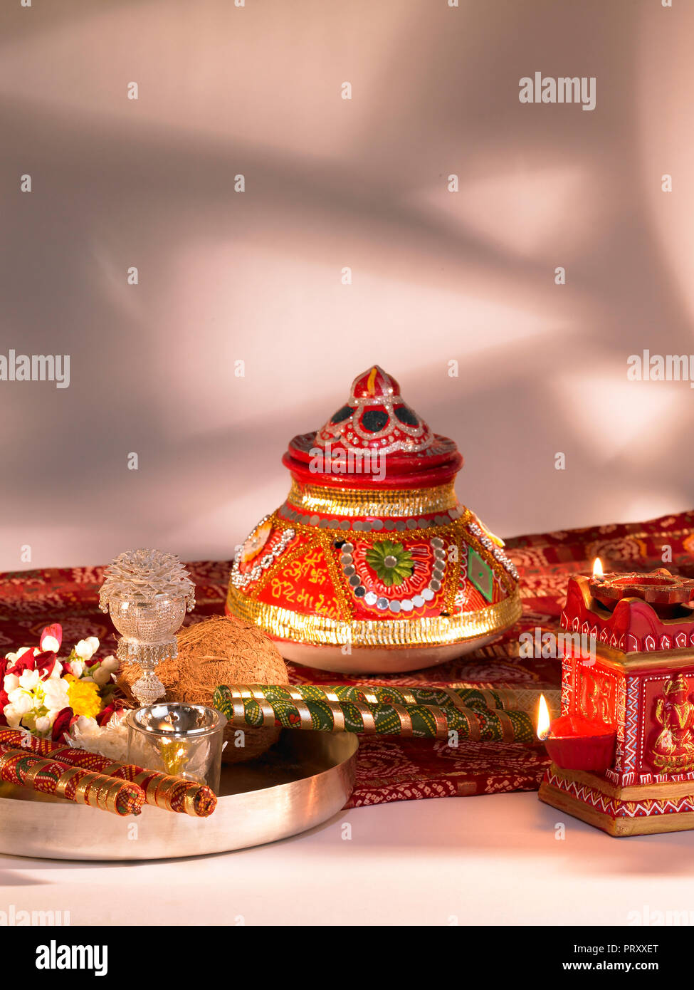 Ein Stilleben von DASSERA FESTIVAL OBJEKTE IN MUMBAI INDIEN ZEIGEN EINE KALASH/POT, DIYAS, Süßigkeiten, BANDHANI, SAREE, SILBER THALI mit Kokosnuss, DIYA, Blume Stockfoto