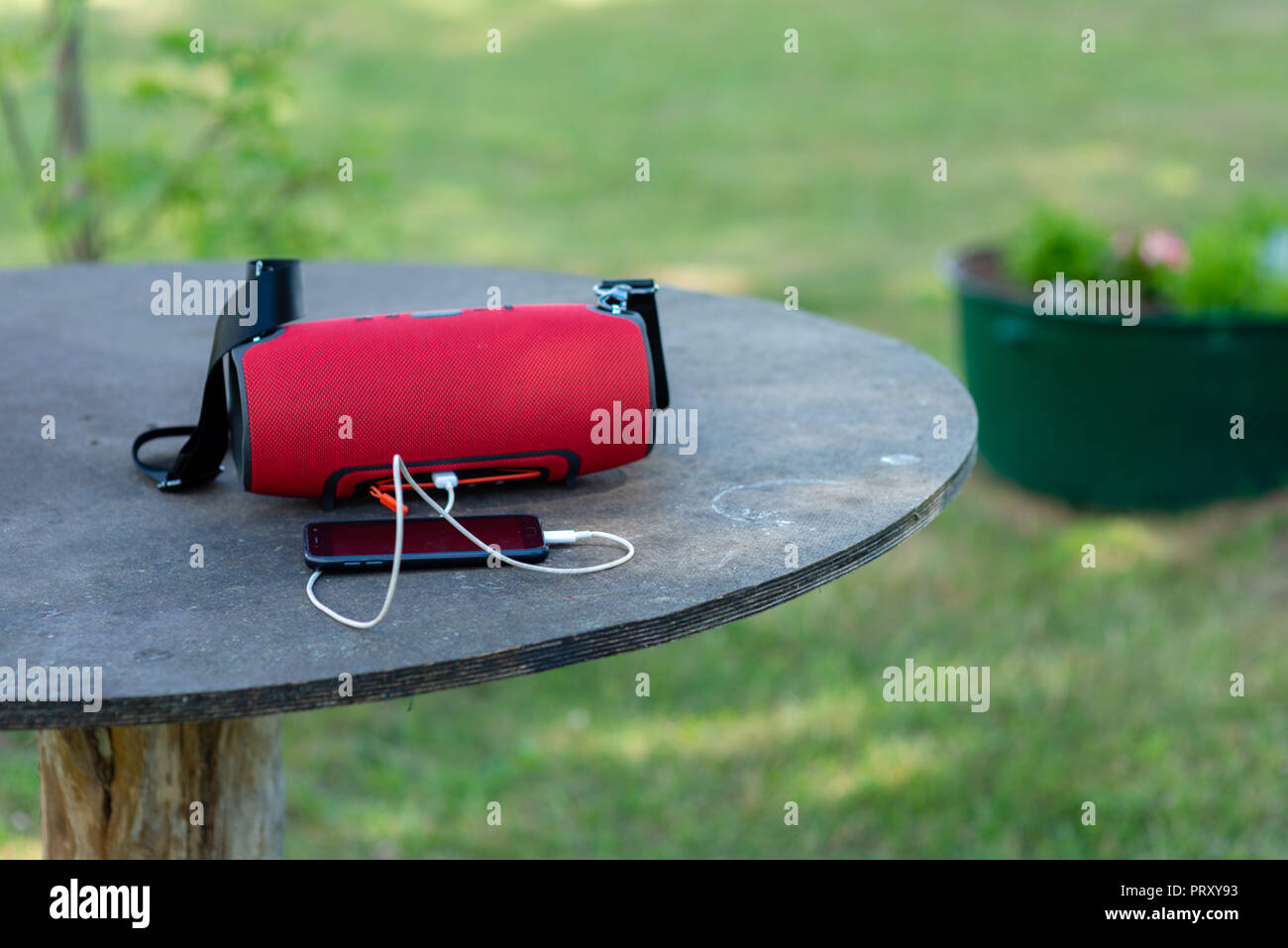 Smartphone mit tragbaren Lautsprechern ist auf einem hölzernen Tisch gelegt. Stockfoto