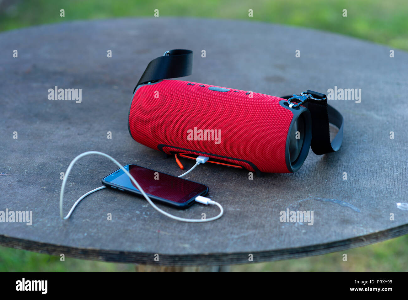 Smartphone mit tragbaren Lautsprechern ist auf einem hölzernen Tisch gelegt. Stockfoto