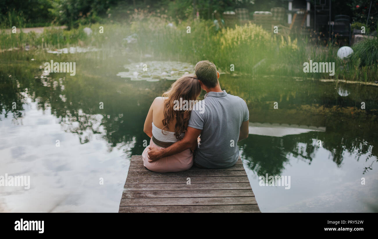 Ansicht der Rückseite des glücklichen Paares sitzt an einem See Stockfoto