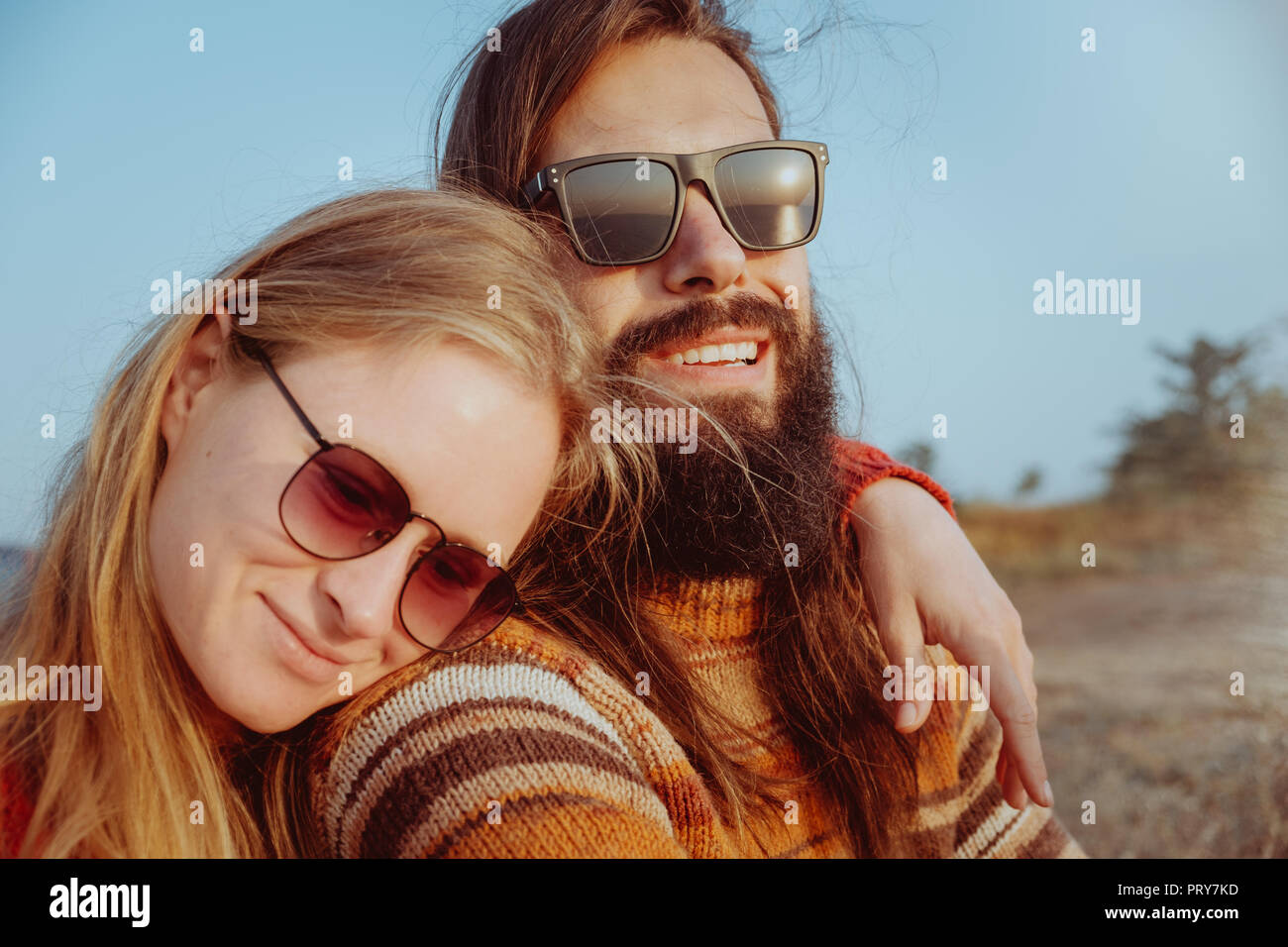 Lächelnd hipster Paar in Sonnenbrille umarmen und Spaß im Freien in Sunrise. Mann und die blonde Frau mit Bart. Stockfoto