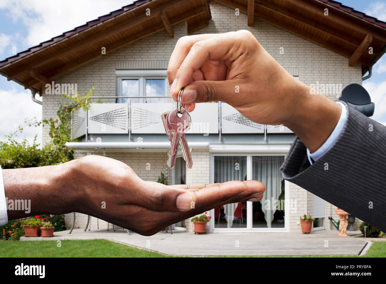 In der Nähe von Real Estate Agent geben Schlüssel zum Client vor dem Haus Stockfoto