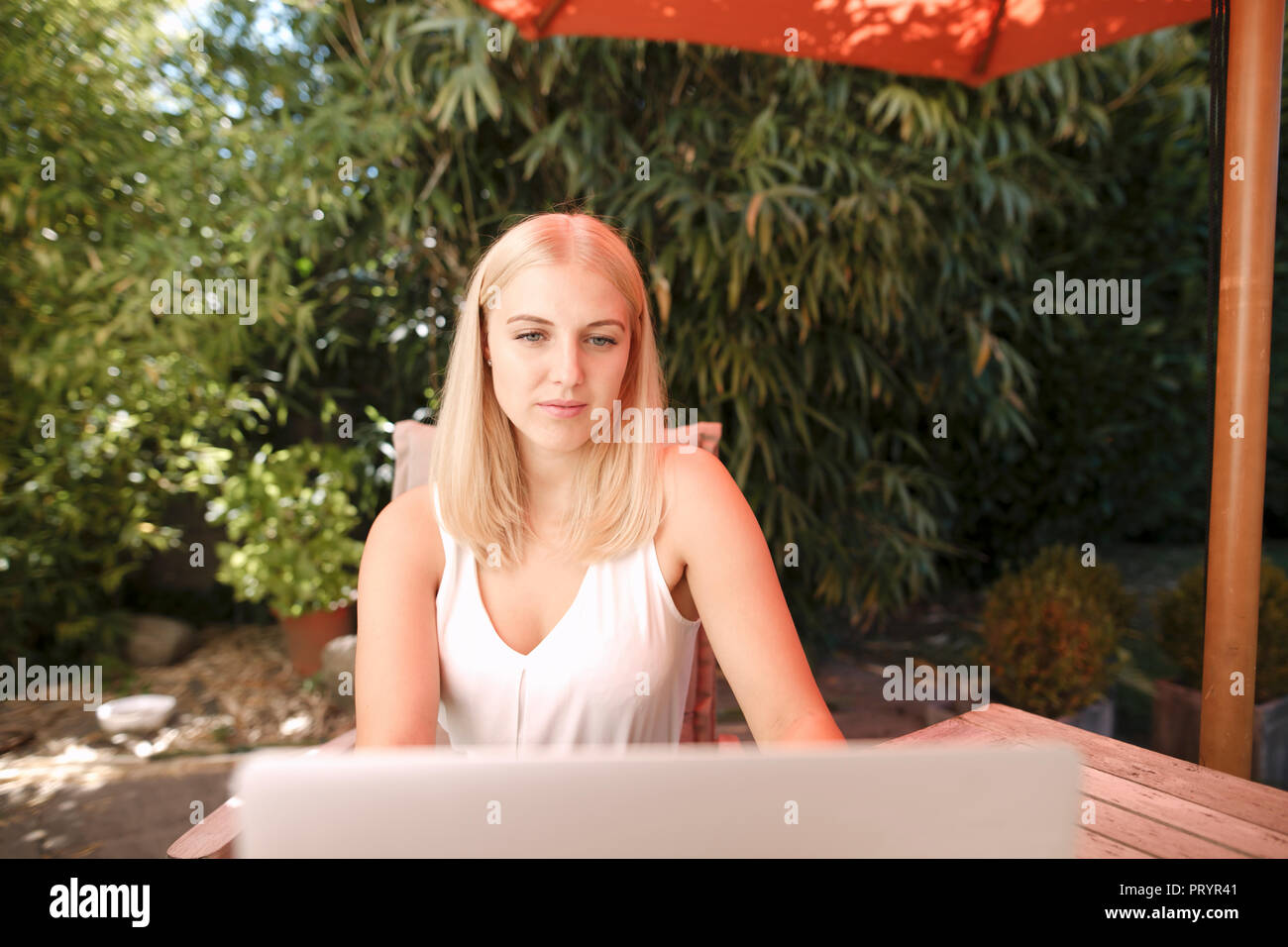 Junge Frau mit Laptop im Garten Stockfoto