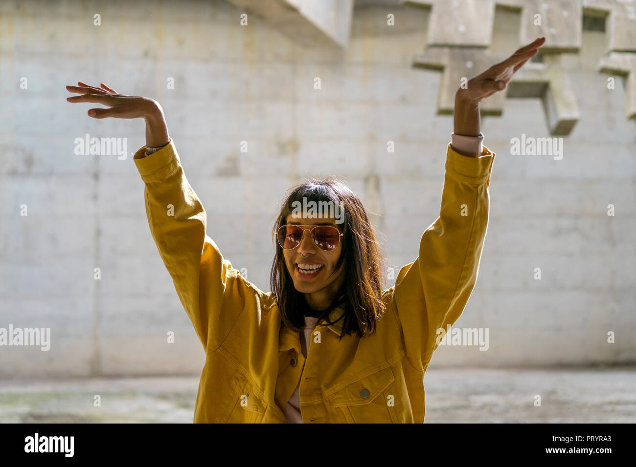 Junge Frau singen, Anheben der Arme Stockfoto
