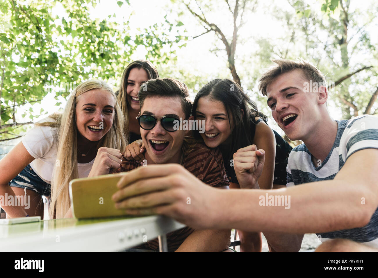 Gruppe der glücklichen Freunde auf der Suche nach Handy im Freien Stockfoto