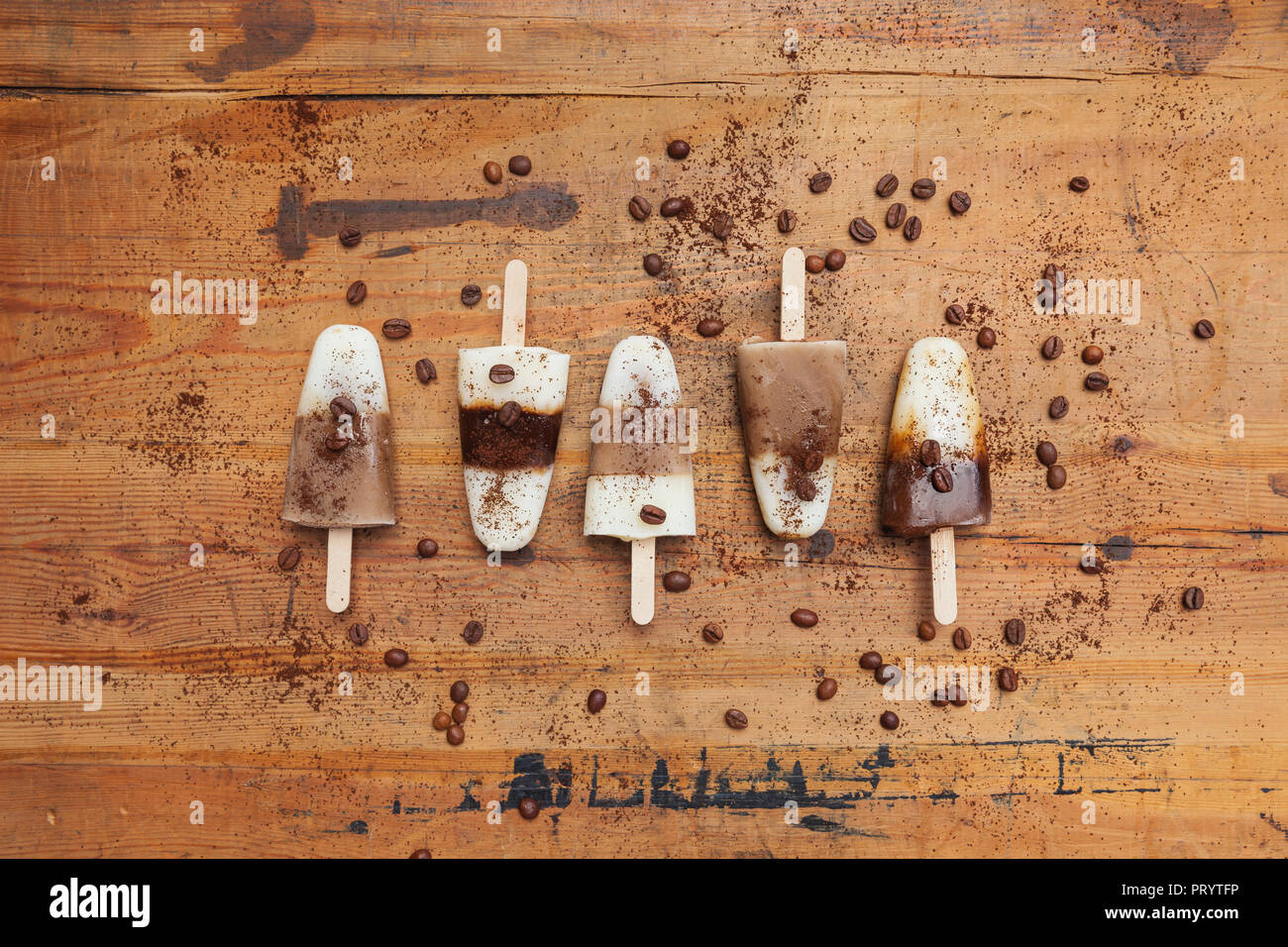 Hausgemachte Espresso Macchiato, Latte Macchiato und Cappuccino Eis am Stiel mit Kaffeebohnen auf hölzernen Hintergrund Stockfoto