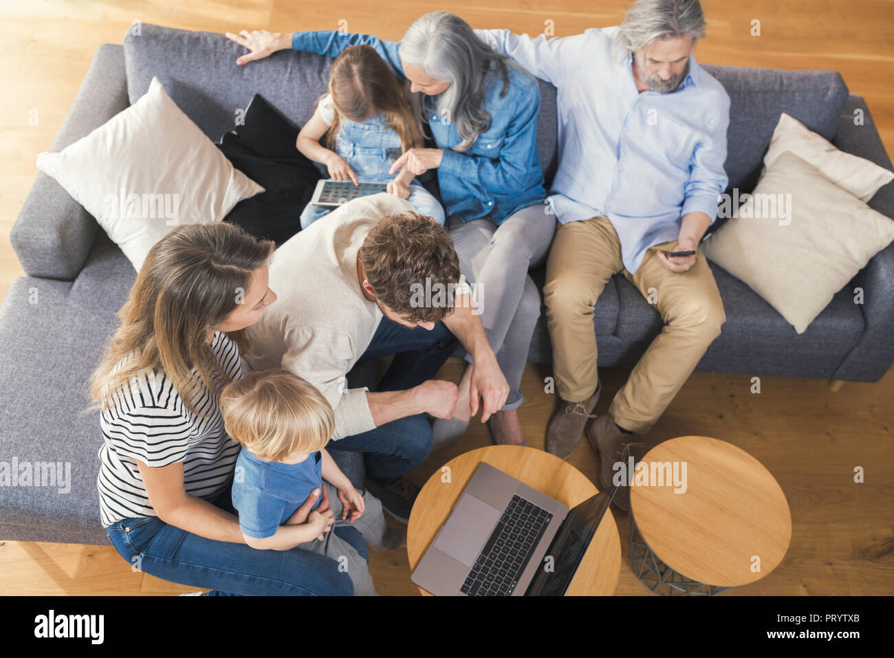 Erweiterte Familie sitzt auf der Couch, mit mobilen Geräten Stockfoto