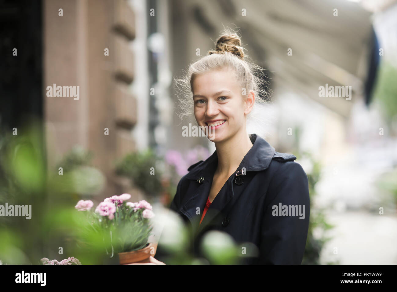 Portrait von lächelnden jungen Frau Wahl Topfpflanze vor einem Blumenladen Stockfoto