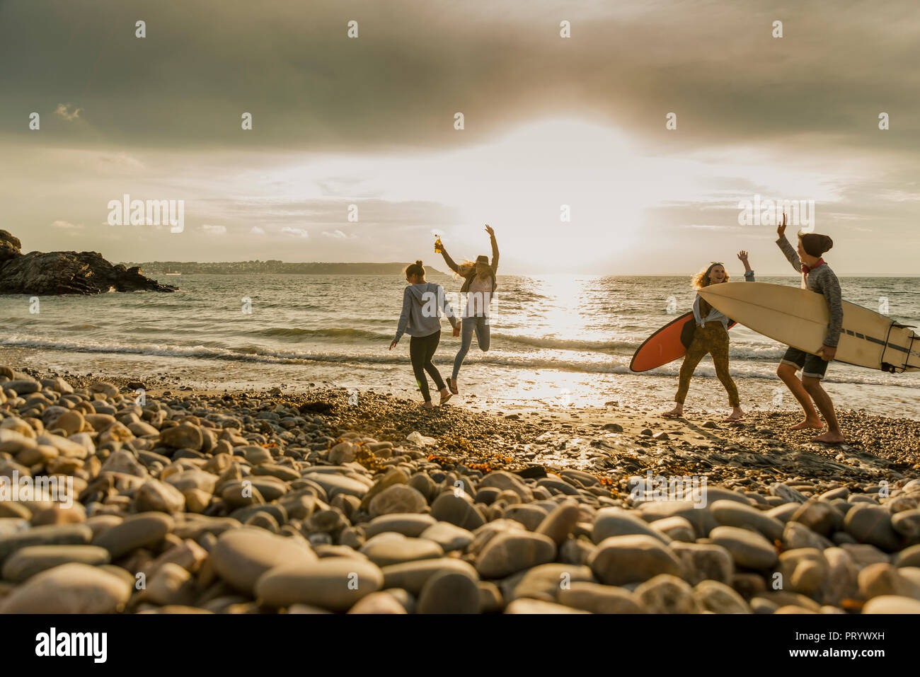 Aufgeregt Freunde mit Surfbrettern auf steinigem Strand Stockfoto