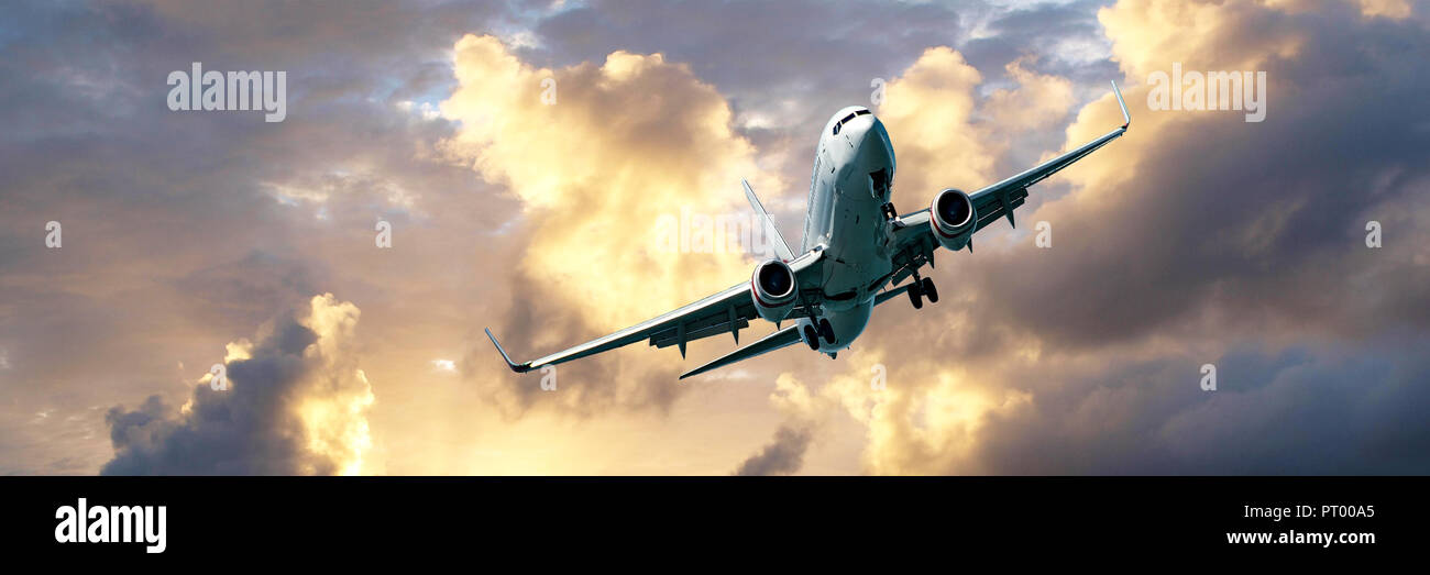 Ein Passagier Jet Airliner fliegen overhead Nahaufnahme mit einem goldenen gelb gefärbte Cumulus cloud Bildung in einer grau-blauen Himmel. Atmosphärischer Schönheit. Stockfoto