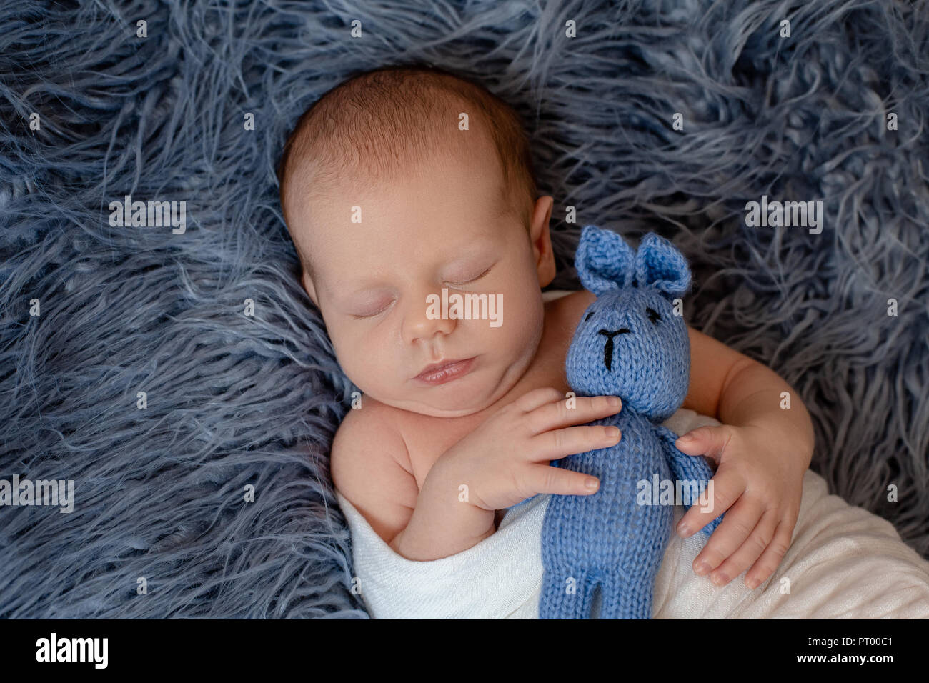 Neugeborenes Baby Boy im Bett. Neu geborene Kind unter einem weißen gestrickten Decke schlafen
