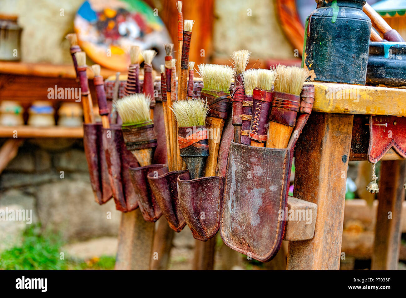 ARTIST'S TASCHE VON PINSELN. Die Rustikalen Maler Pinsel in verschiedenen Formen und Größen in einem alten Leder Tasche auf einer Seite eines Tisches befestigt. Stockfoto