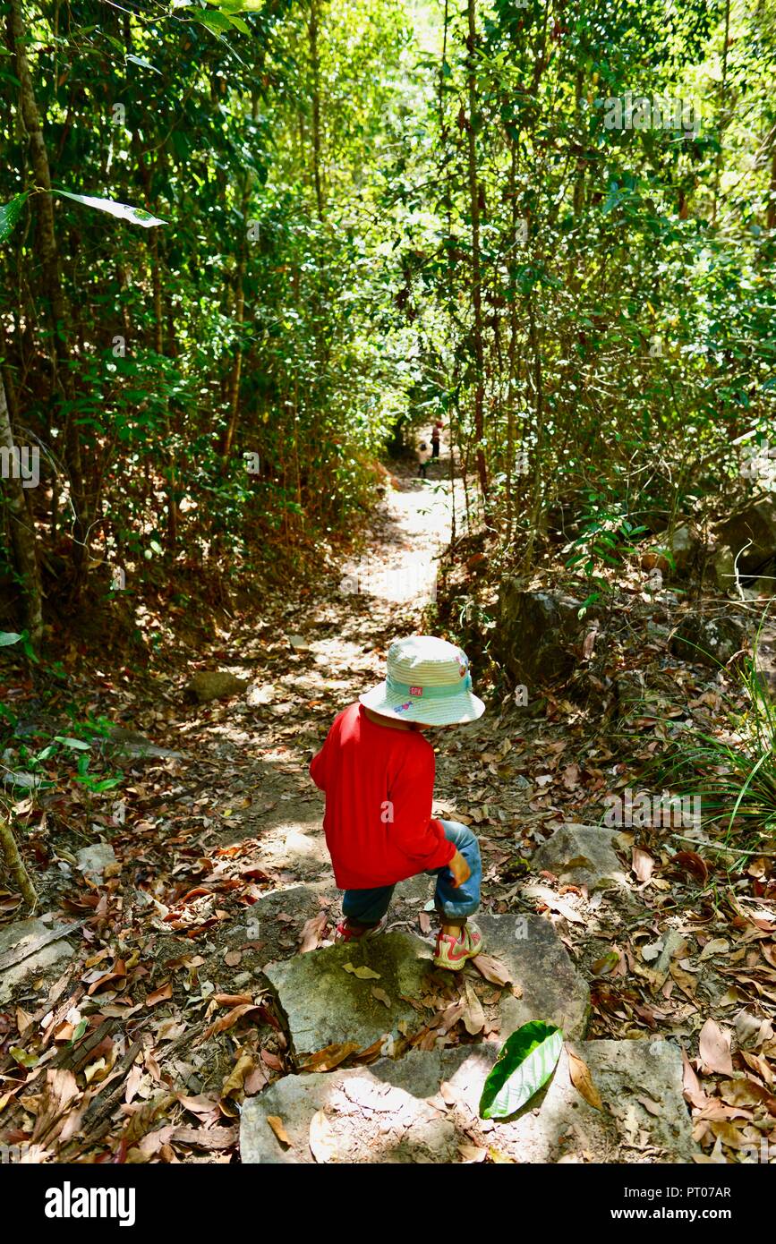 Ein Kind das Tragen der roten gehen durch einen Wald, Dalrymple Lücke, QLD, Australien Stockfoto